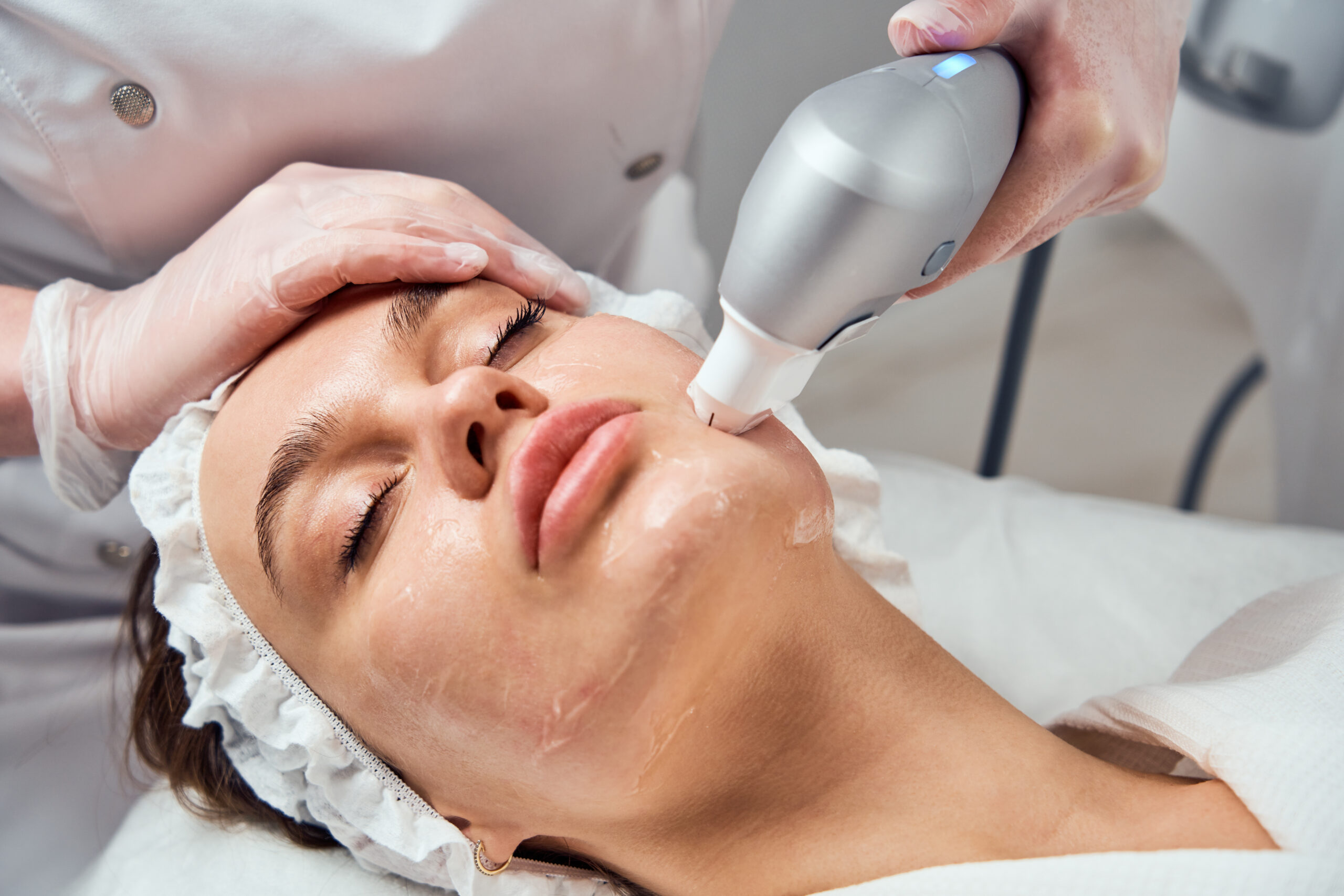 Paciente deitada recebendo tratamento facial com aparelho